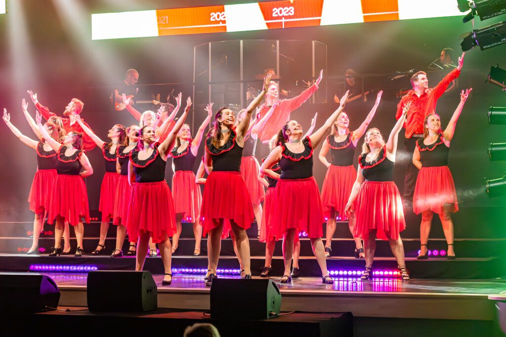 Koorleden dansen en zingen op het podium in een traditioneel Spaanse outfit