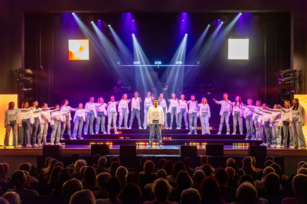 Koorleden dansen en zingen op het podium